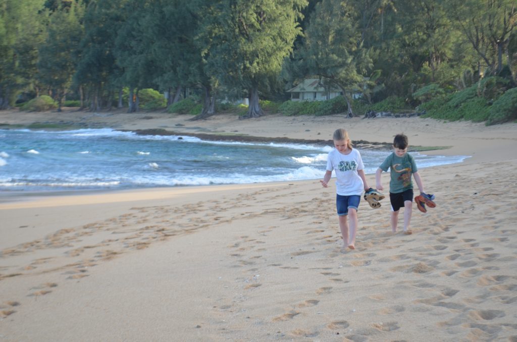 kids walking on the beach in front of the Hanalei Colony Resort