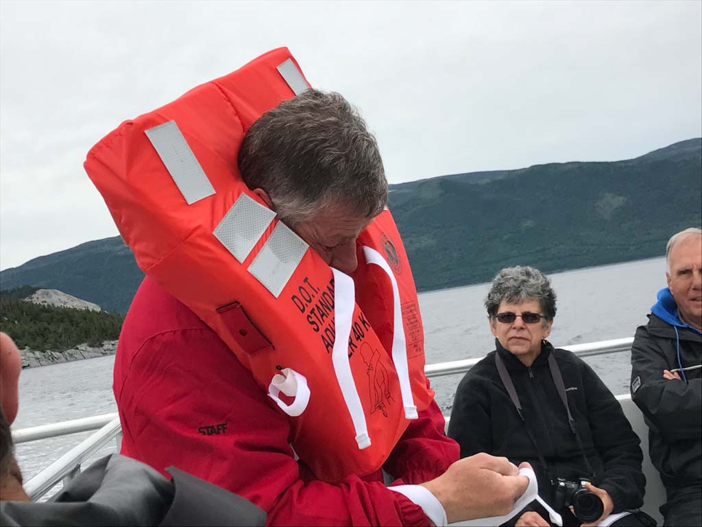Host showing how to wear a life jacket on our Gros Morne Boat Tours