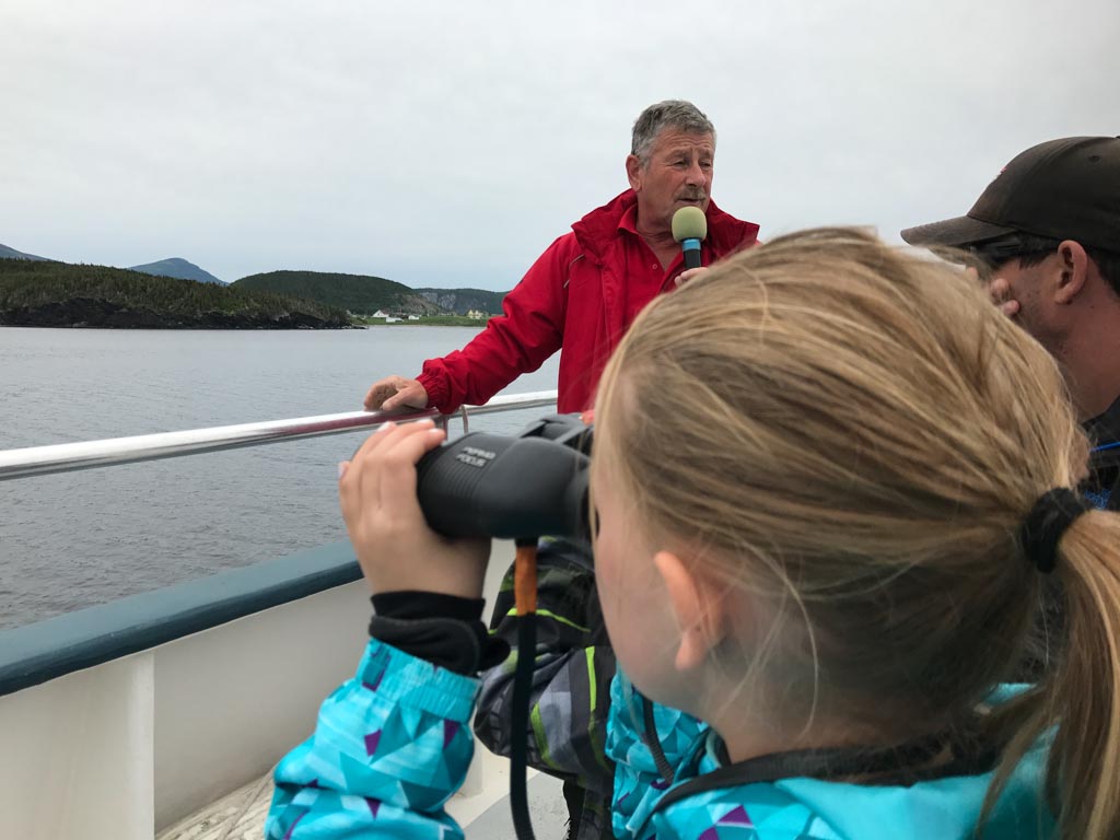 Girl using self focusing binoculars on our Gros Morne boat tours