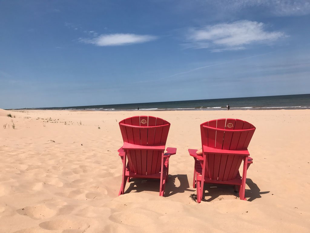 Red lawn chairs on the beach at the PEI National Park