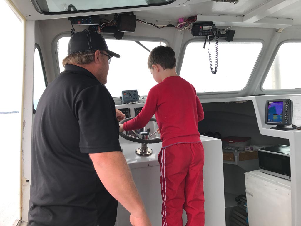 Boy driving lobster boat with Top Notch Charters