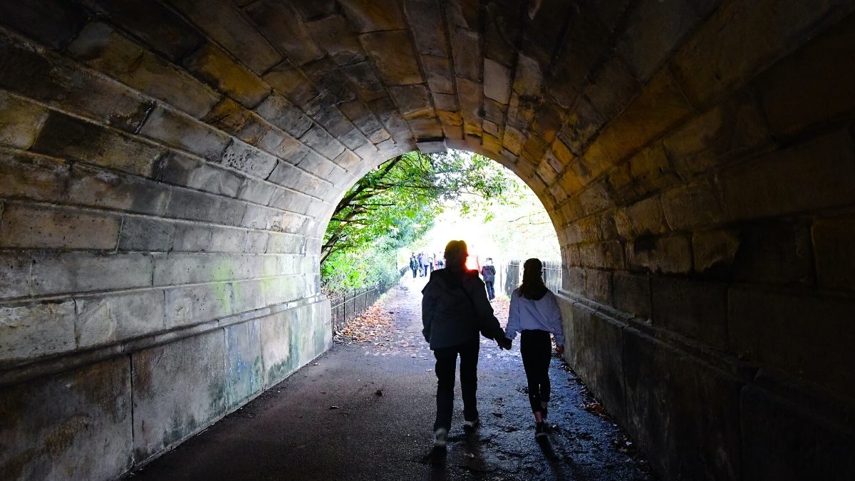 woman and child holding hands while walking through a tunnel