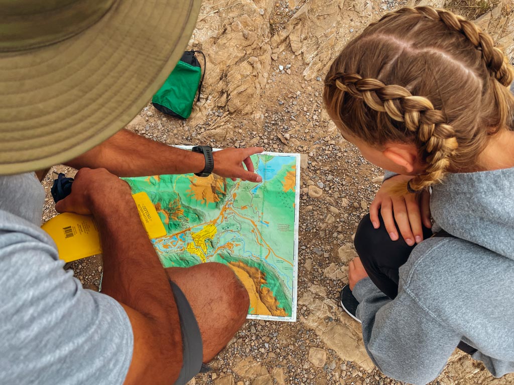 girl looking at hiking map that is held by the guide