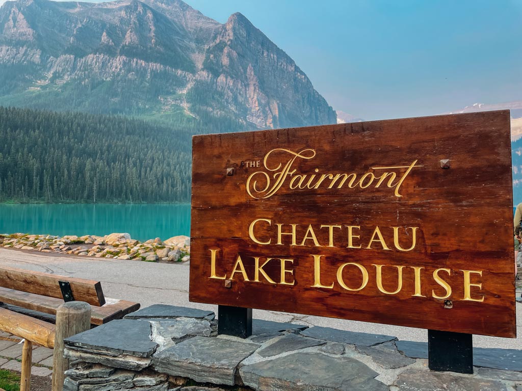 fairmont chateau lake louise sign with the lake and mountains in the background